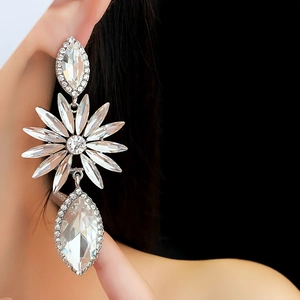 Gros plan de boucles d'oreilles fleurs argentées avec cristaux sur un mannequin