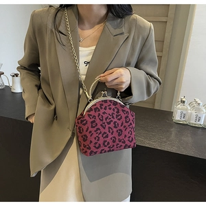 Detail of burgundy leopard plush shell bag with metal frame and chain on beige blazer