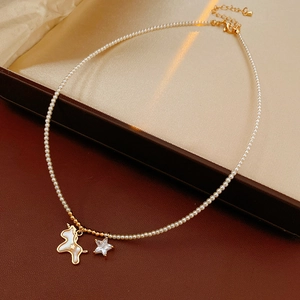 Detail of beaded pearl necklace with golden unicorn and sparkling star pendants