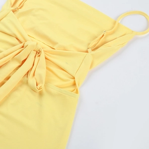 Detail of the pale yellow dress featuring delicate spaghetti straps and a ribbon bow tie