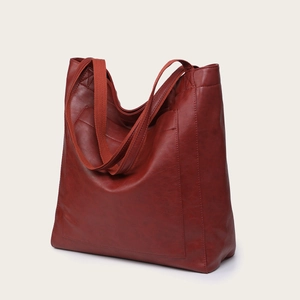 Détail d'un grand sac cabas rouge en similicuir avec poche avant et bandoulière tissée