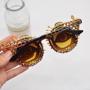 Vintage steampunk sunglasses with gold crown gear frame and tan lenses shown in hand