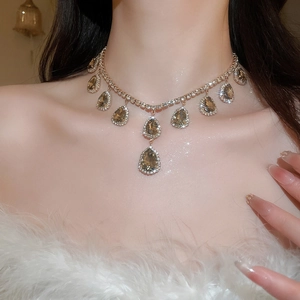 Detailed view of champagne pear-shaped crystal necklace on a model for a luxury look