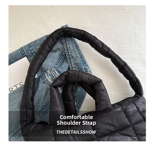 Detail of padded shoulder strap on black quilted puffer tote bag with soft texture
