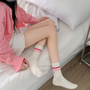 Close-up of white mid-calf socks with pink stripes and a smile logo in a cozy setting