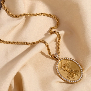 Macro view of gold angel relief pendant with crystal inlay on twisted chain