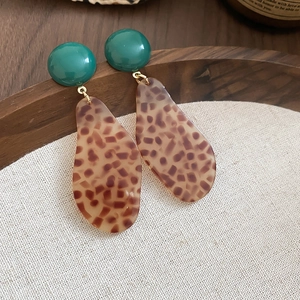 Detailed view of vintage acetate leopard print teardrop earrings on a rustic linen background