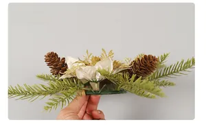 Side view of golden Christmas candle ring with pine cones and festive fabric flowers
