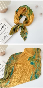 Detail of accordion pleated scarf featuring abstract tie-dye print in mustard and blue
