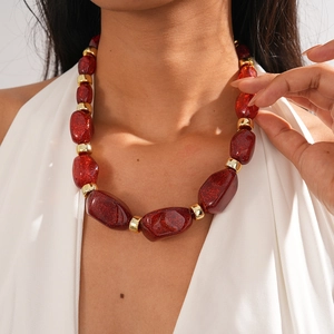Close-up of red resin beads and golden metallic spacers on a chunky vintage necklace