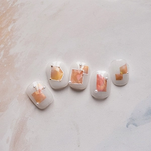Detail of shell texture nail stickers with orange amber patterns and white pearls