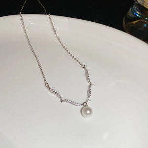 Detail of cubic zirconia flower pendant with elegant white pearl on a silver chain