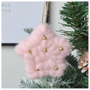 Close-up of pink plush star Christmas ornament with gold beads hanging on a tree branch