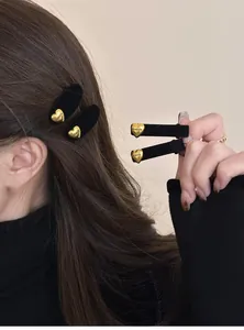 Dettaglio di fermagli per capelli neri floccati con cuori d'oro sui capelli