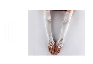 Detail of elegant long satin bridal gloves with lace embroidery and bead accents