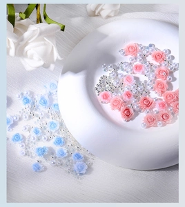 Detail of 3D resin roses and mixed pearls for DIY nail art on a white ceramic plate