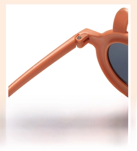 Detail of durable metal hinges and smooth matte orange frames on kids sunglasses