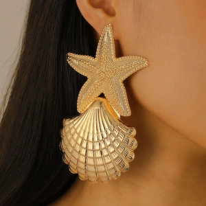 Macro view of oversized gold starfish and scallop earrings with granular metal textures