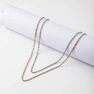 Detail showing gold and silver water wave chain necklaces draped on a white roll