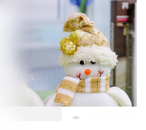 Close-up of plush Christmas snowman with gold striped knit hat and festive carrot nose