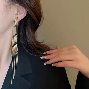 Close-up of long layered silver tassel earrings with black beads on a female model