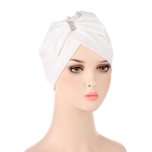 Detail of white pleated turban featuring a sparkling rhinestone bow decoration