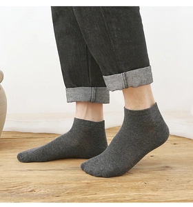 Close-up of a male model wearing dark grey cotton ankle socks on light wood flooring
