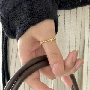 Close-up of a minimalist golden bamboo texture ring worn on the thumb for a chic look