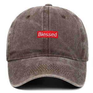 Detail of red rectangular embroidered patch with Blessed text on washed grey baseball cap
