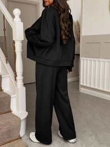 Rear view of women's black leisure jacket and pants set on indoor stairs