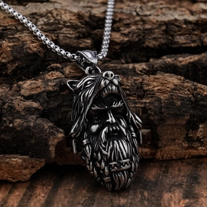 Close-up of a silver Viking wolf head helmet pendant on a rustic tree bark background