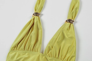 Detail of yellow halter neck dress featuring golden triple-ring hardware and pleated fabric
