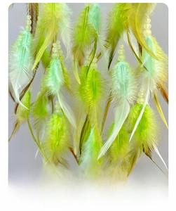Detail showing green feathers and frosted beads on a hand-woven dream catcher