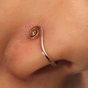 Macro shot of rose gold spiral non-piercing U-shaped nose ring on female model