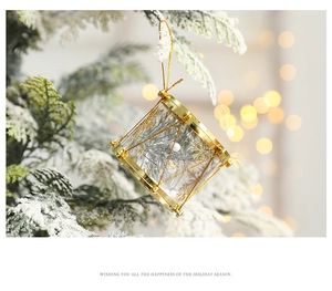Close-up of a festive gold Christmas drum ornament hanging on a snowy tree branch