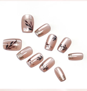 Detail of pink cat eye press on nails with gold foil lines and black leaf patterns