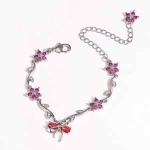 Detailed view of pink zircon flower and bow bracelet in polished silver finish