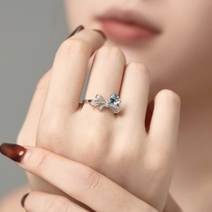 S925 silver ring featuring asymmetrical bow design with heart-shaped light blue gemstone