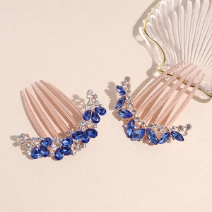 Rose gold hair combs with blue teardrop crystals and floral rhinestones on beige background