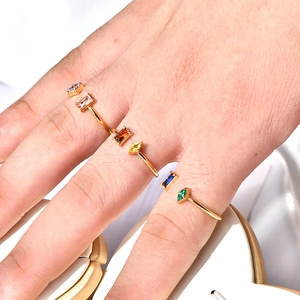 Detail of adjustable gold-plated double-line rings with colorful gemstones on fingers