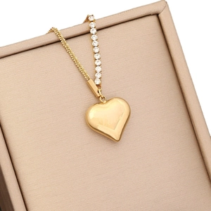 Gold heart pendant necklace with rhinestones and Love engraving in a beige jewelry box