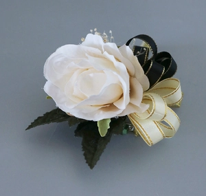Vue détaillée d'une boutonnière en rose de soie blanche avec rubans dorés et feuilles vertes