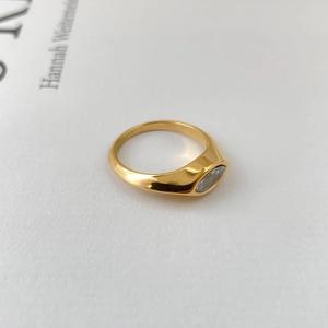Macro shot of a minimalist gold ring featuring a marquise-cut zircon on polished metal