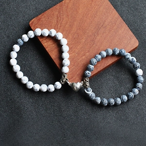 Macro shot of couple beaded bracelets with magnetic heart buckle on wood background