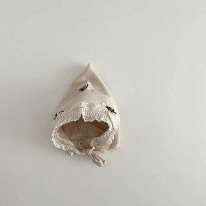 Close-up of knit baby hat with delicate white lace trim and dark brown bow accents