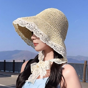 Detail of hand-woven straw sun hat featuring white lace trim and adjustable chin ties