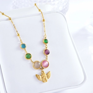 Detail of bohemian angel necklace with colorful cat eye stones on a white jewelry box