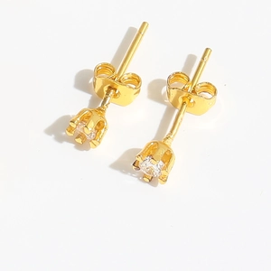Detail of golden stud earrings featuring prong-set round cubic zirconia on white backdrop