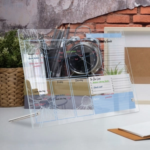 Detailed view of a transparent acrylic weekly planner with sunflower design on a desk