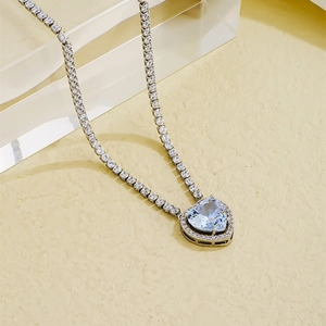 Close-up of heart pendant necklace with sky blue stone on silver tennis chain